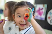 Child smiling with coloured hand in class 