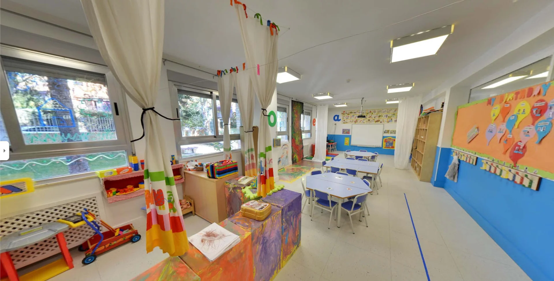 A bright, welcoming classroom with child-sized tables, learning areas, and colorful displays.
